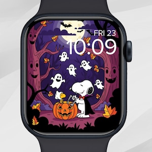 May include: A black smartwatch displays a Halloween-themed graphic. The image features Snoopy, a carved pumpkin, ghosts, and a full moon. The time is 10:09, and the date is Friday, the 23rd. The background includes purple and brown trees.