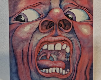 May include: Square album cover art featuring a watercolor painting of a screaming face with wide eyes and an open mouth. The face is primarily red and purple, with white teeth and a black stand.