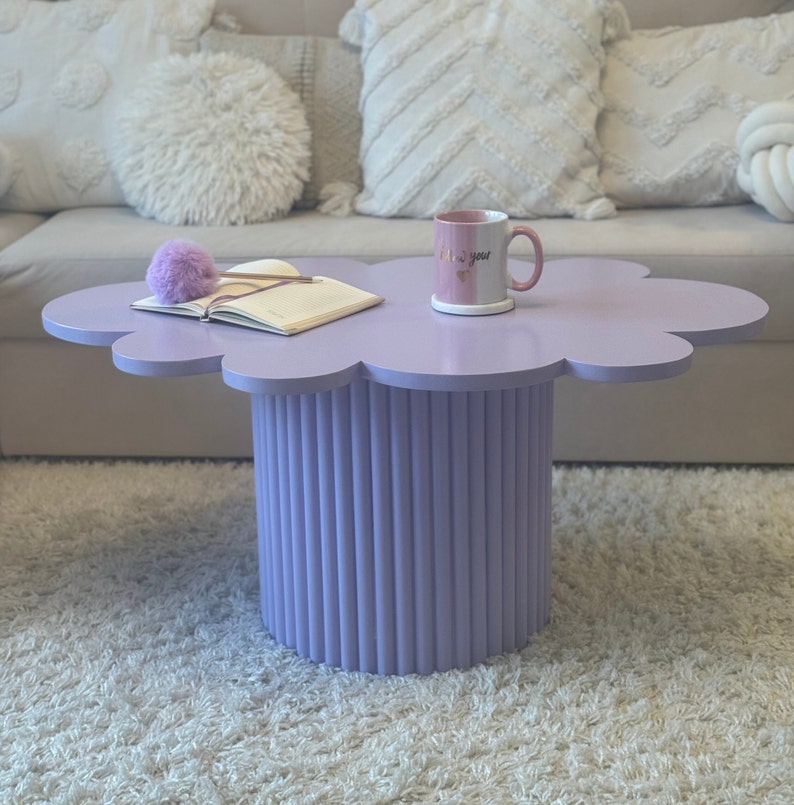 Cloud-shaped coffee table in pastel lavender colour. The top of the table looks like a little cloud. The leg of this table is round and made of half round wooden mouldings. Dimensions: 58cmx40cmx80cm.