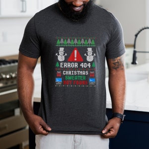 May include: Dark gray t-shirt with a humorous Christmas design. The design features a red warning sign, snowmen, Christmas trees, and the text "ERROR 404 CHRISTMAS SWEATER NOT FOUND" in green and white. A fun, festive holiday tee.