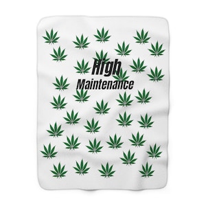 May include: White fleece blanket with a green marijuana leaf pattern and the text "High Maintenance" in black.