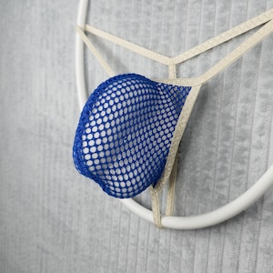 May include: A thong featuring a bright blue mesh pouch with a distinct grid pattern. The garment is constructed with thin, light beige elastic straps that form a T-back design, providing a minimalist structure and a secure fit for the wearer.