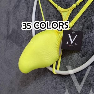 May include: A neon yellow thong swimsuit with thin straps and a matching top. The text "35 COLORS" is displayed in white. A black tag with a white "V" logo is attached.