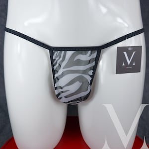 Op de afbeelding: Zwarte en witte zebraprint mesh string ondergoed met zwarte elastische bandjes en een klein zwart label met de letter "M" erop.