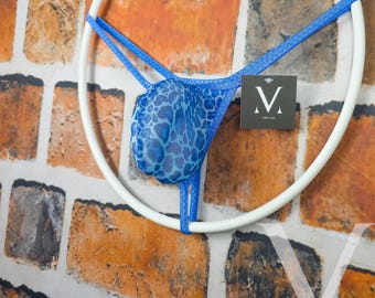 May include: Blue thong underwear with a leopard print design, displayed on a white circular frame. The underwear is made of a sheer fabric and has blue straps. A small tag with the letter "V" is visible.
