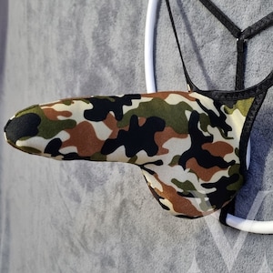 May include: A camouflage patterned jockstrap with black trim. The jockstrap is hanging from a white ring.