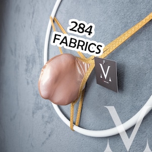 May include: A thong featuring a metallic rose-gold pouch and thin gold straps, displayed on a white circular frame. A black tag with the letter M is attached. The text 284 FABRICS is visible in white letters with a black outline above the garment.