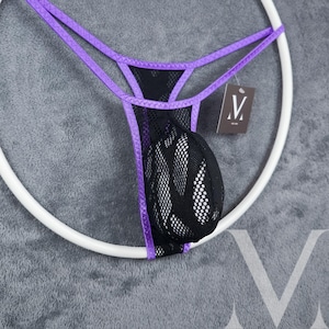 Könnte beinhalten: Schwarzer Mesh-String-Tanga mit lila Besatz und Trägern. Die Unterwäsche hat einen Beutel und hängt an einem weißen kreisförmigen Kleiderbügel. Ein kleines Etikett mit einem Logo hängt am Kleidungsstück.