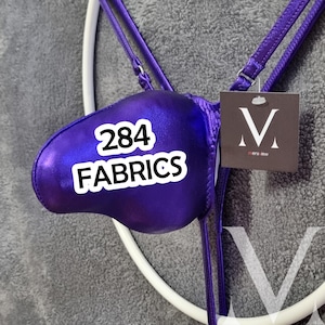May include: A metallic purple pouch underwear featuring thin adjustable straps and a square tag with the letter M and the text mensview. The fabric has a shiny finish and the text 284 FABRICS is overlaid on the front of the purple pouch.