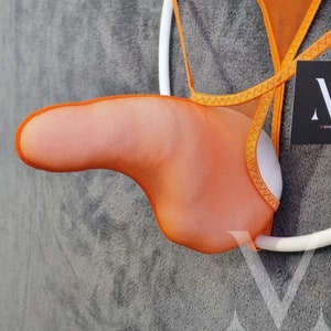 May include: Orange mesh jockstrap with white trim and a white elastic band. The jockstrap is hanging on a white hanger.