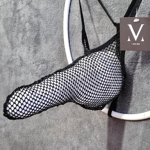 May include: Black and white mesh underwear with a pouch design. The underwear is suspended on a white ring and features a tag with the letter "M" and the text "mens jew".