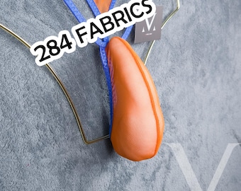 Puede incluir: Un tanga con una bolsa de malla de color naranja brillante y ribete azul, expuesto en una percha de alambre dorado. El texto 284 FABRICS aparece superpuesto en blanco. La prenda incluye una pequeña etiqueta cuadrada con un logo M blanco.
