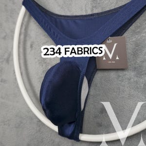 Könnte beinhalten: Marineblaue Unterwäsche mit Pouch-Design. Das Kleidungsstück trägt den Text "234 FABRICS" in Weiß. Ein weißer Kleiderbügel befindet sich im Hintergrund. Ein Etikett mit dem Buchstaben "V" ist an der Unterwäsche befestigt.