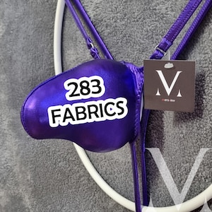 Könnte beinhalten: Glänzendes, lila Dessous-Set mit dünnen Trägern und einem Etikett mit "M" und "mens view". Der Text "283 FABRICS" ist auf der Vorderseite zu sehen. Der Hintergrund ist hellgrau.