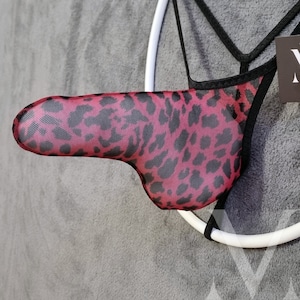 May include: A black and pink leopard print mesh thong with a black strap and a white ring.