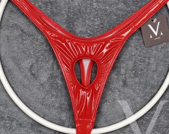 May include: A red patent leather thong featuring a glossy finish and a central cutout detail. The garment includes a small dark tag with a white letter M logo attached to the side. The item is displayed over a white circular frame.