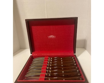 Juego de 8 cuchillos para carne Cutco 59 con mango de baquelita marrón y caja de presentación de madera.