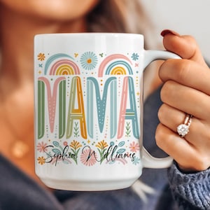 May include: White ceramic mug with a colorful design featuring the word "MAMA" with rainbow arches and floral accents. The mug is personalized with the name "Sophia Williams".