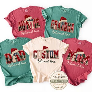 May include: Five short-sleeved t-shirts in red, green, and cream colors. Each shirt features a large block-letter graphic with a red and green plaid pattern, topped with a red Santa hat. The text reads AUNTIE, GRANDMA, DAD, CUSTOM, and MOM.