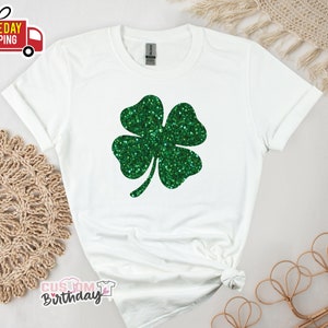 May include: White t-shirt with a green glitter four-leaf clover design.