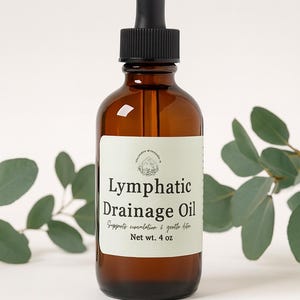 Puede incluir: Una botella de vidrio marrón de Aceite de Drenaje Linfático con un cuentagotas negro. La etiqueta dice "Lymphatic Drainage Oil" y "Supports circulation & gentle detox." Peso neto 113 g.