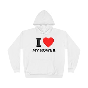 Puede incluir: Sudadera con capucha blanca con el texto "I ♥ MY ROWER" en negro y rojo. La "I" es negra, el corazón es rojo y el texto está en negrita, sin serifa. La sudadera tiene un bolsillo delantero y una capucha con cordón.