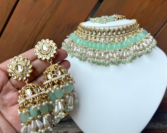 May include: A gold and green beaded necklace and earrings set. The necklace has multiple layers of beads, including pearls, green glass beads, and gold accents. The earrings are dangle earrings with a similar design to the necklace.