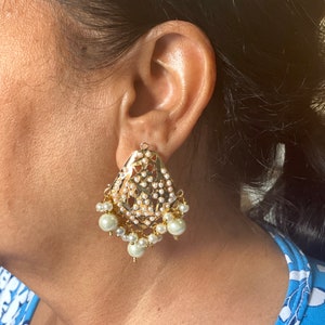 May include: Gold tone earrings with a delicate filigree design and pearl accents.