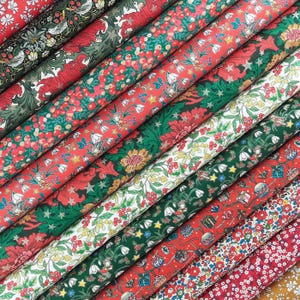 Könnte beinhalten: Eine Sammlung von Stoffrollen mit verschiedenen festlichen Mustern, darunter rote und grüne Blumenmotive, Stechpalmenbeeren, Misteln, Schneeglöckchen, kleine Geschenkboxen und Sternmotive, die in diagonalen Reihen angeordnet sind.
