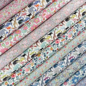 Peut inclure: Plusieurs rouleaux de tissu imprimé, présentant des motifs floraux et animaliers. Les imprimés incluent des girafes, des éléphants et des fleurs dans des tons roses, bleus et verts. Le tissu est probablement du coton ou une matière légère similaire.