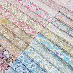 Puede incluir: Una colección de muestras de tela floral en varios colores, incluyendo rosa, azul, amarillo y morado. Los patrones de tela presentan pequeñas flores y hojas, dispuestas en filas diagonales. La estética general es delicada y femenina.