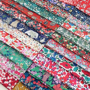 Może przedstawiać: Kolekcja kolorowych próbek tkanin z kwiatowymi i wzorzystymi wzorami. Tkaniny charakteryzują się różnorodnością kolorów, w tym czerwonym, niebieskim, zielonym i różowym, ze szczegółowymi ilustracjami kwiatów, gwiazd i zwierząt. Idealne do projektów patchworkowych lub rękodzielniczych.
