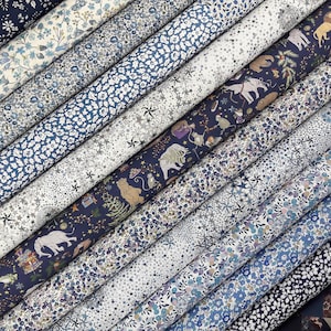 Può includere: Una collezione di rotoli di tessuto disposti in diagonale, caratterizzati da vari motivi tra cui fitte stampe floreali blu e bianche, disegni stellati e un tessuto blu scuro decorato con illustrazioni di elefanti, scimmie e orsi.