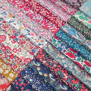 May include: A selection of floral fabric swatches in a range of colours, including red, pink, blue, and green. The fabrics display diverse flower designs, such as roses and poppies. The swatches are arranged diagonally, showcasing a variety of patterns.