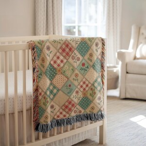 May include: A patchwork baby blanket draped over a white crib. The blanket features a variety of patterned squares in beige, red, green, and blue, with floral and gingham designs. The blanket has a fringed edge.