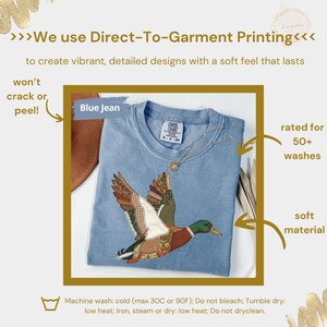 K&ouml;nnte beinhalten: Hellblaues T-Shirt mit detailliertem Enten-Design. Das Shirt tr&auml;gt den Schriftzug "Blue Jean" und ist f&uuml;r &uuml;ber 50 W&auml;schen geeignet. Das Bild enth&auml;lt auch Text &uuml;ber den Direktdruck auf Textilien und Pflegehinweise.