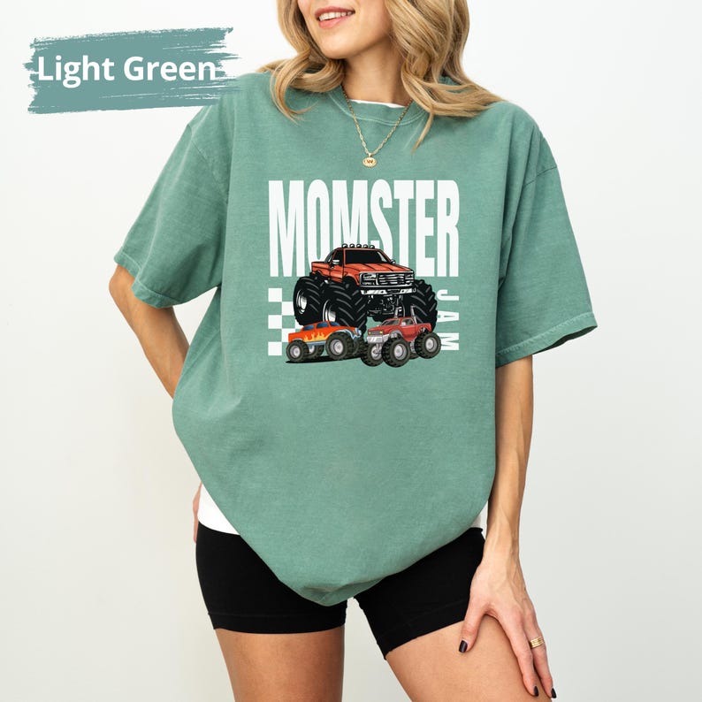 May include: A light green t-shirt featuring a graphic of a monster truck and the text "MOMSTER JAM".