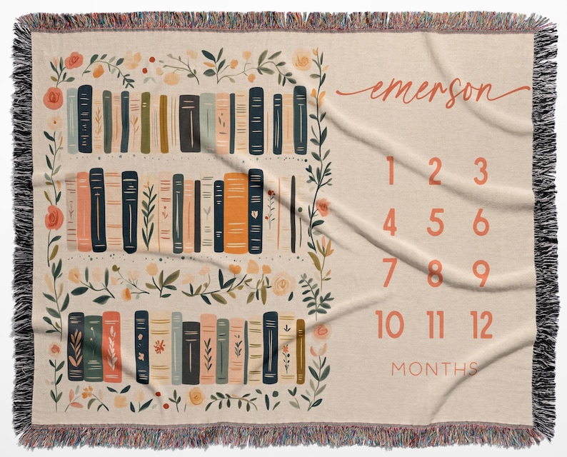 Op de afbeelding: Een beige baby mijlpaaldeken met een boekenplankontwerp en bloemaccenten. De deken heeft een boekenplankillustratie met verschillende boekkleuren en de naam "emerson" in cursief. Cijfers 1-12 worden weergegeven voor maandelijkse foto's.