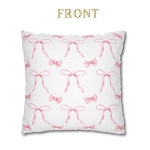 Puede incluir: Funda de almohada blanca con un patr&oacute;n de lazos rosas. La funda de almohada tiene la palabra "FRONT" impresa en dorado.
