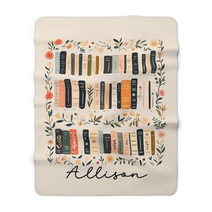 May include: A cream-colored fleece blanket with a floral border and a bookshelf filled with colorful books. The name "Allison" is written in black script at the bottom.