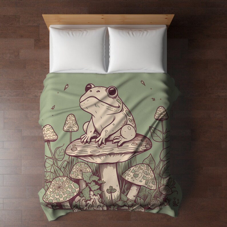 May include: A green and brown bedding set with a frog sitting on a mushroom. The frog is green with brown spots and has a white belly. The mushroom is brown with white spots. The bedding set is surrounded by green leaves and other mushrooms.