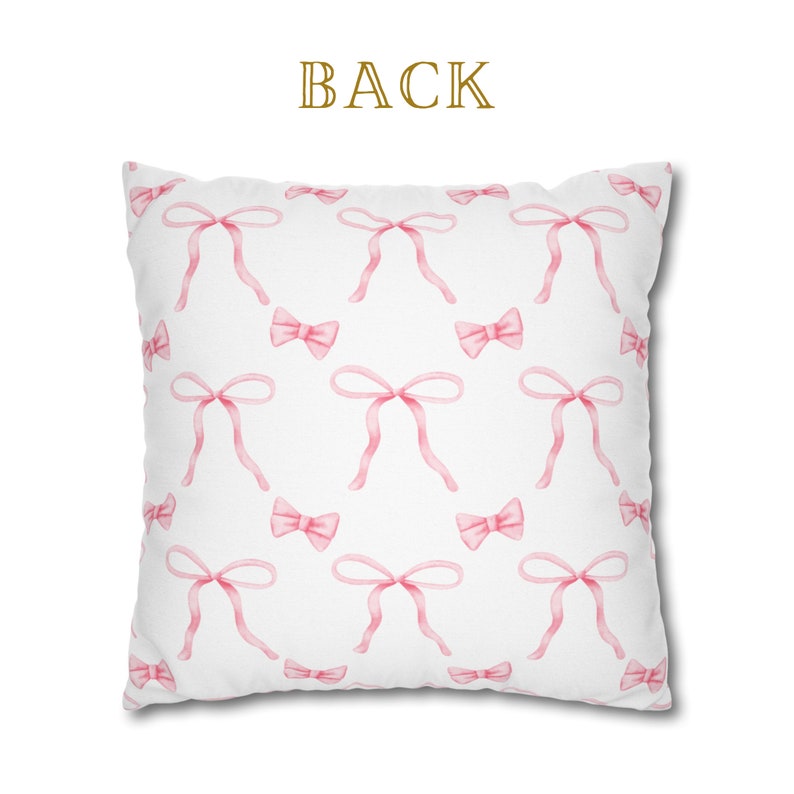 Puede incluir: Almohada blanca con un patr&oacute;n de lazos rosas. La parte posterior de la almohada tiene la palabra "BACK" impresa.