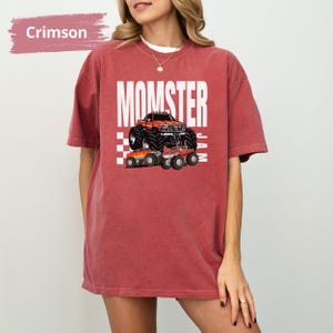 May include: Oversized t-shirt in crimson red with a white graphic of a monster truck and the text "MOMSTER JAM".