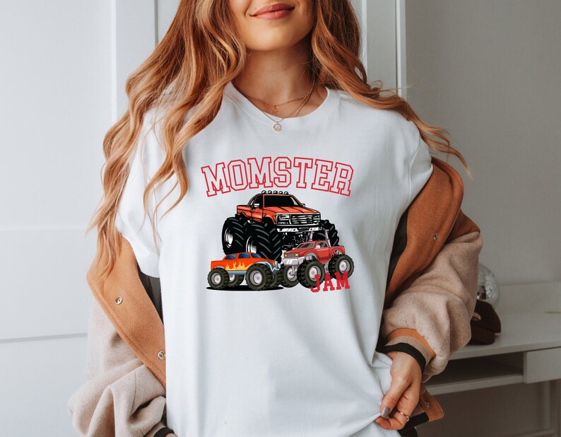 May include: White t-shirt with a red graphic of a monster truck and the text "MOMSTER JAM".