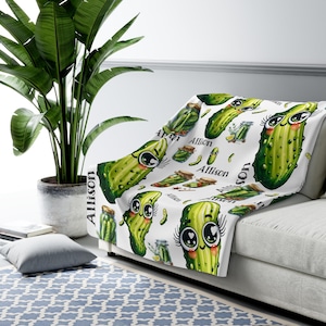 May include: White fleece throw blanket with a repeating pattern of green cartoon pickles with eyelashes and the name "Allison" printed on the blanket.