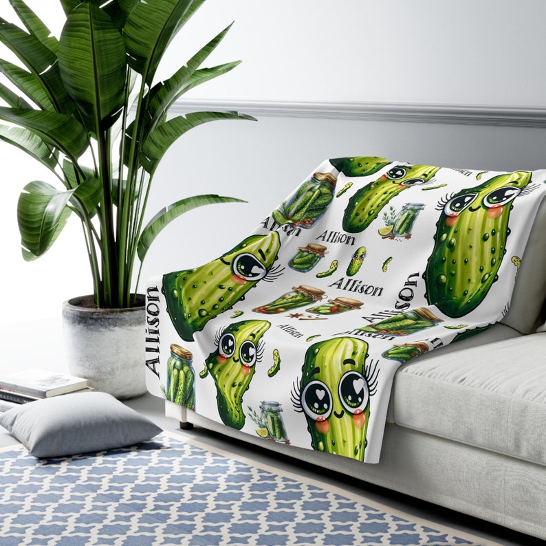 May include: White fleece throw blanket with a repeating pattern of green cartoon pickles with eyelashes and the name "Allison" printed on the blanket.