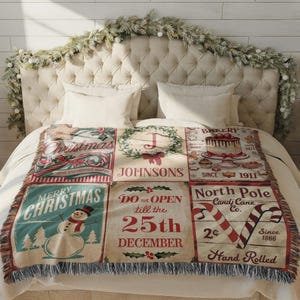 May include: A woven throw blanket featuring a grid of six Christmas-themed panels with illustrations of a snowman, a cake, candy canes, and text including Merry Christmas, Johnsons, and Do not open till the 25th December.