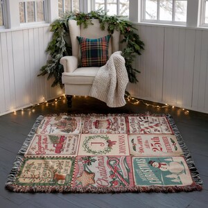May include: A rectangular woven throw blanket featuring a grid of nine Christmas-themed panels with illustrations of gingerbread houses, a red truck, a snowman, candy canes, and text including Merry Christmas and North Pole.