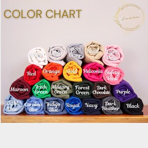 May include: Color chart showing 20 different colors of fabric swatches rolled up. The colors include white, ash, sport gray, sand, light pink, red, orange, gold, heliconia, safety pink, maroon, Irish green, military green, forest green, dark chocolate, purple, light blue, Carolina blue, indigo blue, royal blue, navy, dark heather, and black.
