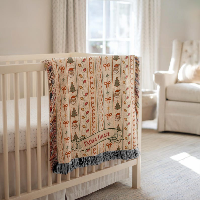May include: A woven throw blanket featuring a repeating Christmas pattern of Santa Claus faces, green pine trees, red bows, and light bulbs on a cream background. The blanket includes a decorative banner with the name Emma Grace printed in red.
